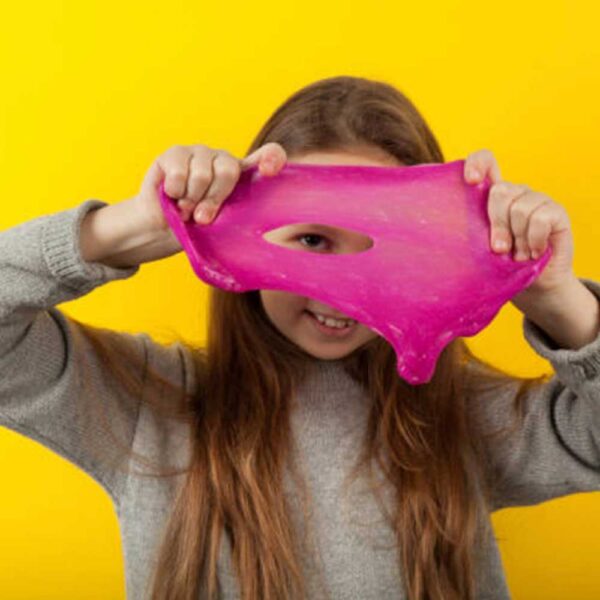Young girl with pink slime in front of yellow wall